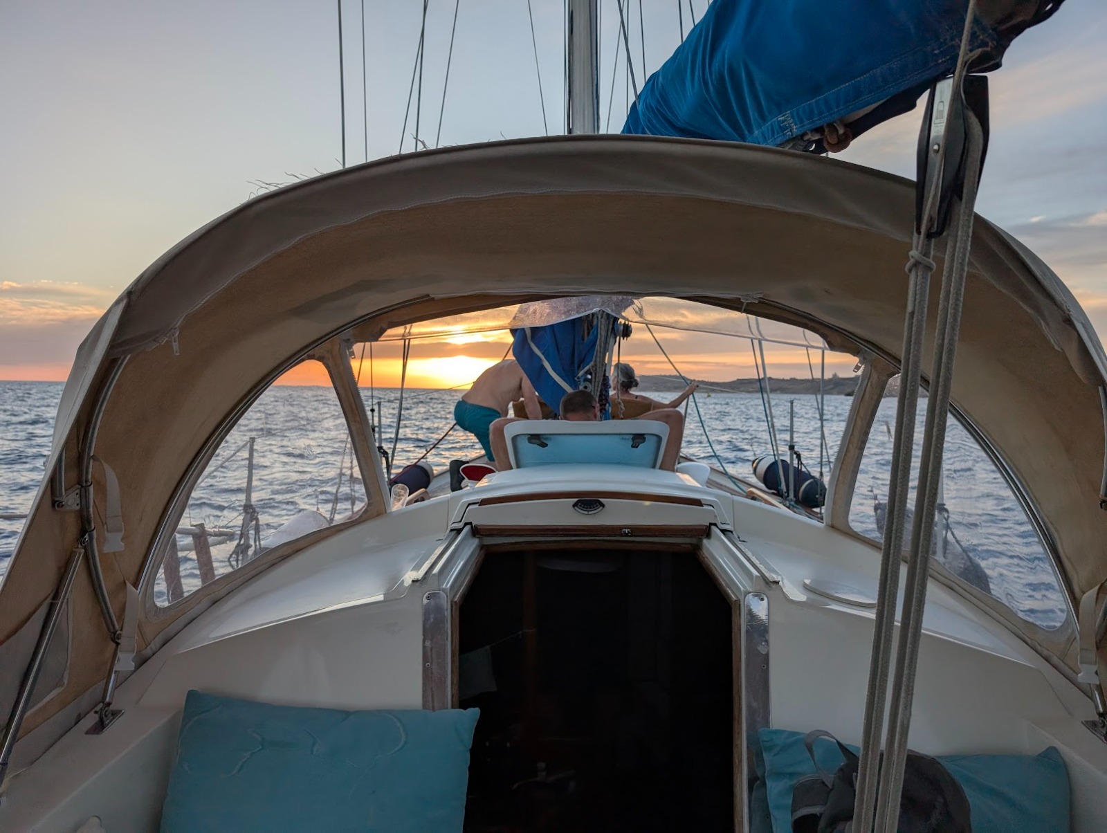The boat at anchor, sunset sky reflected in calm water.