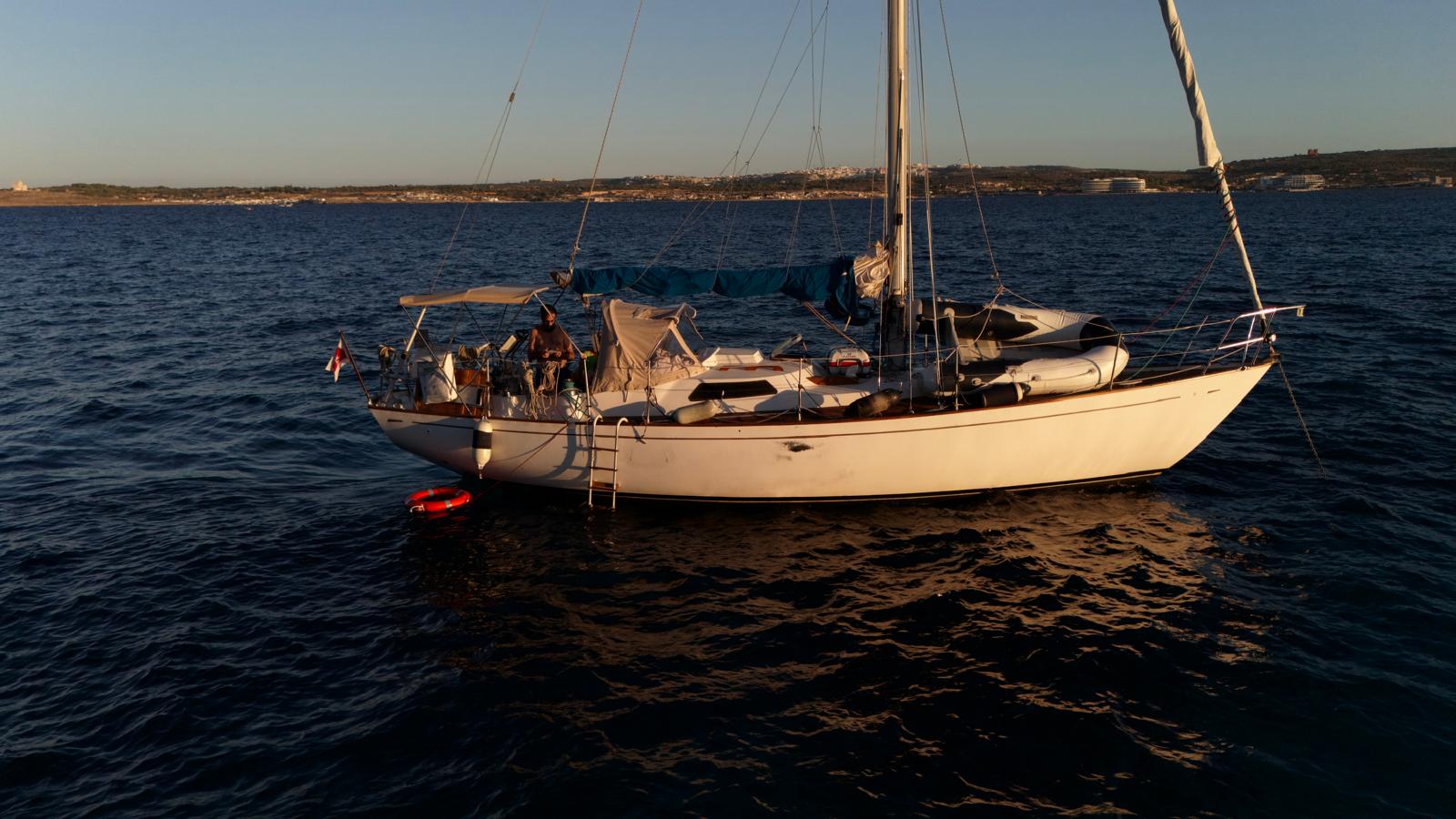 Full profile of the Biscay 36 at anchor in golden light.